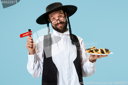 Image of The young orthodox Jewish man with black hat with Hamantaschen cookies for Jewish festival of Purim