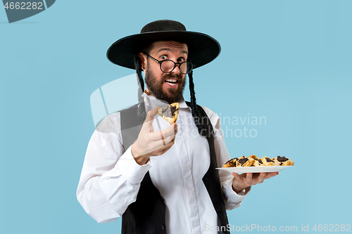 Image of The young orthodox Jewish man with black hat with Hamantaschen cookies for Jewish festival of Purim