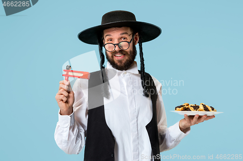 Image of The young orthodox Jewish man with black hat with Hamantaschen cookies for Jewish festival of Purim