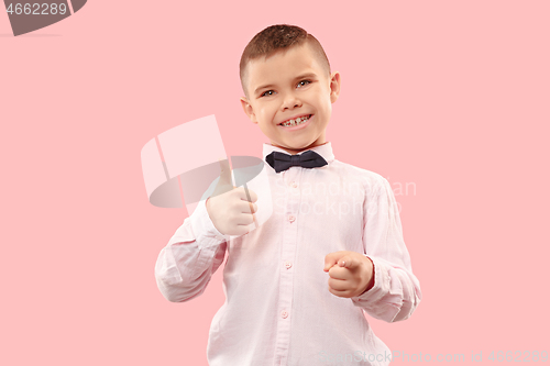 Image of The happy teen boy standing and smiling against pink background.