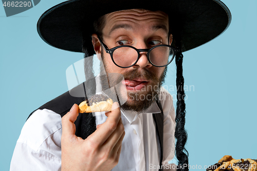 Image of The young orthodox Jewish man with black hat with Hamantaschen cookies for Jewish festival of Purim