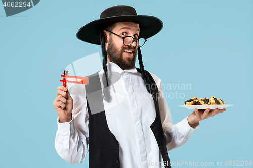 Image of The young orthodox Jewish man with black hat with Hamantaschen cookies for Jewish festival of Purim