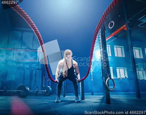 Image of Woman with battle rope battle ropes exercise in the fitness gym.