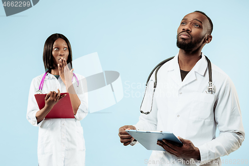 Image of The female and male happy afro american doctors on blue background