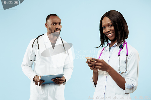 Image of The female and male happy afro american doctors on blue background