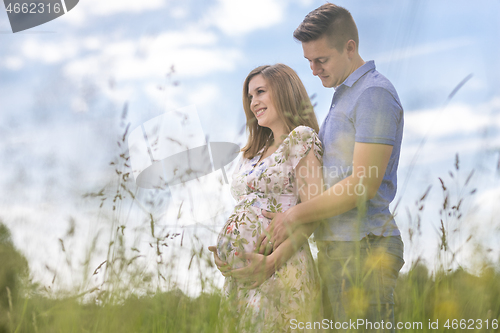 Image of Young happy pregnant couple hugging in nature.