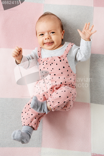 Image of sweet baby girl in pink suit lying on blanket