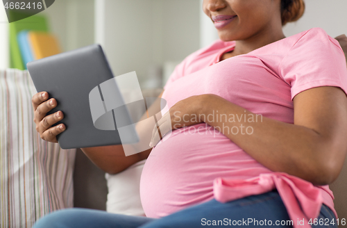 Image of happy pregnant woman with tablet computer at home