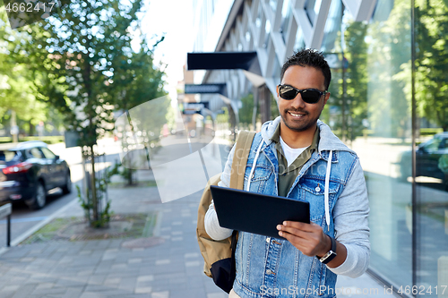 Image of man with tablet pc and backpack on city street