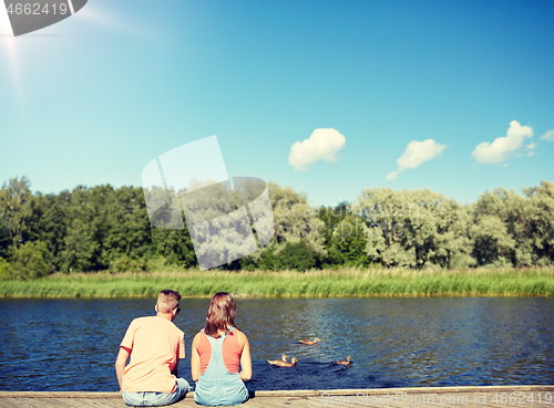 Image of couple on river berth looking at swimming ducks