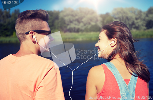 Image of happy teenage couple with earphones on river berth