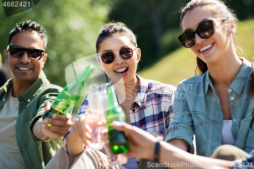 Image of happy friends clinking drinks outdoors in summer