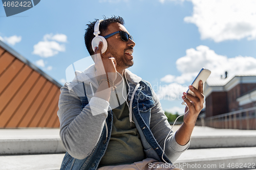 Image of man with smartphone and headphones on roof top