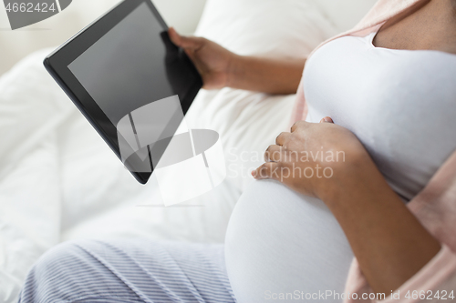 Image of close up of pregnant woman with tablet pc at home