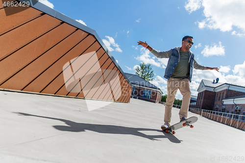 Image of indian man doing trick on skateboard on roof top