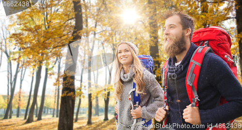 Image of smiling couple with backpacks hiking in autumn