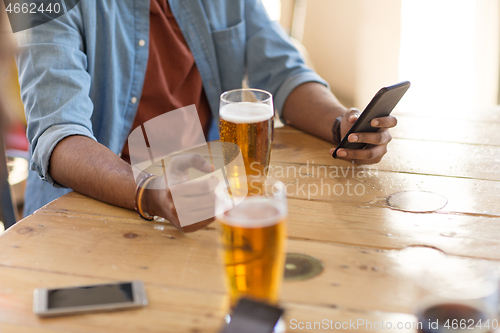 Image of man with smartphone drinking beer at bar or pub