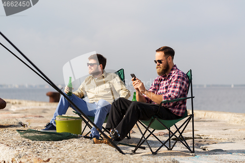 Image of friends with smartphone fishing and drinking beer