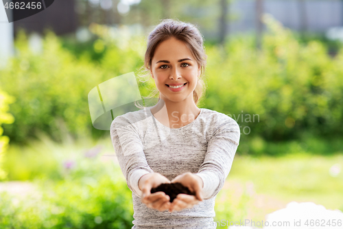 Image of young woman with handful of soil at summer garden