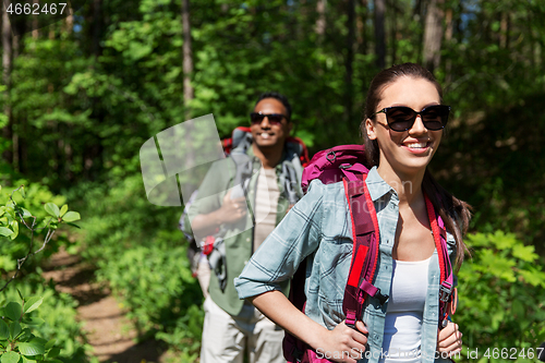 Image of mixed race couple with backpacks hiking in forest