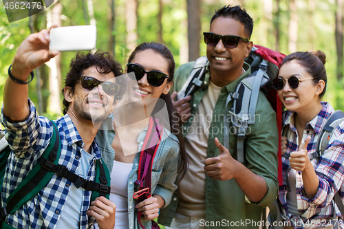 Image of friends with backpacks hiking and taking selfie