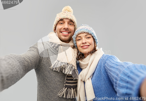 Image of happy couple in winter clothes taking selfie