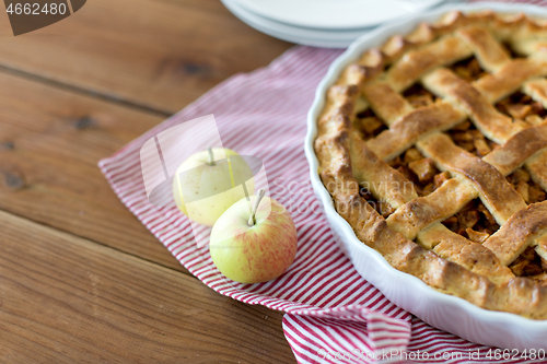 Image of apple pie in baking mold on wooden table