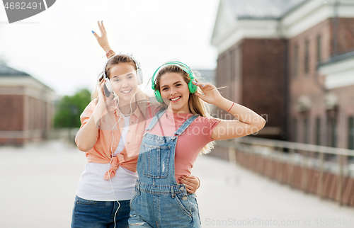 Image of teenage girls or friends in headphones in city