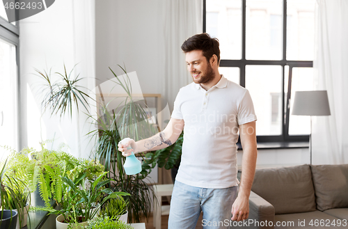 Image of man spraying houseplants with water at home