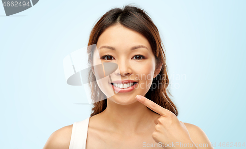 Image of happy smiling young asian woman touching her face
