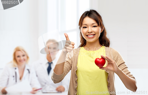 Image of happy asian woman with red heart showing thumbs up