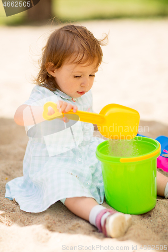 Image of little baby girl plays with toys in sandbox