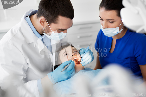 Image of dentist checking for kid teeth at dental clinic