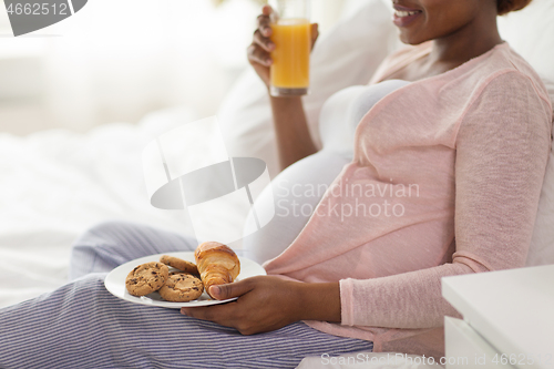 Image of pregnant woman having breakfast in bed at home