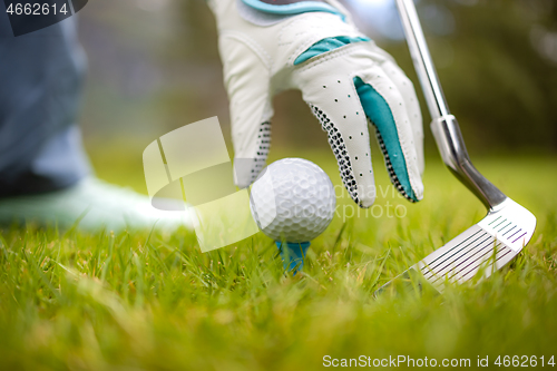 Image of Hand in glove placing golf ball on tee