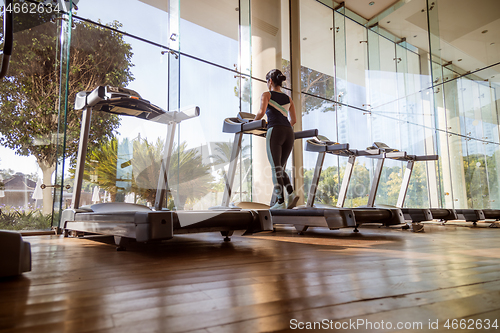 Image of Woman running on treadmill in gym. Ealthy lifestyle.