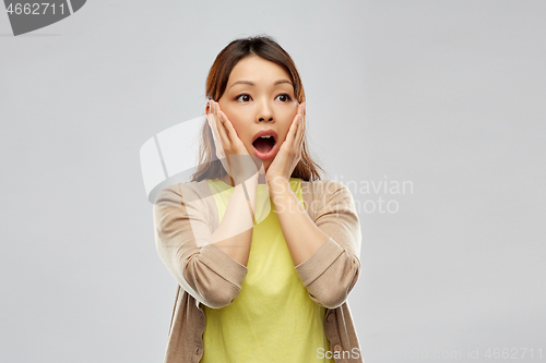 Image of scared asian woman over grey background