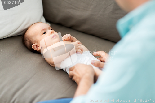 Image of middle aged father changing baby\'s diaper at home