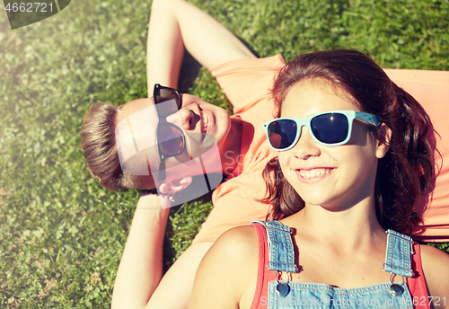 Image of happy teenage couple lying on grass at summer