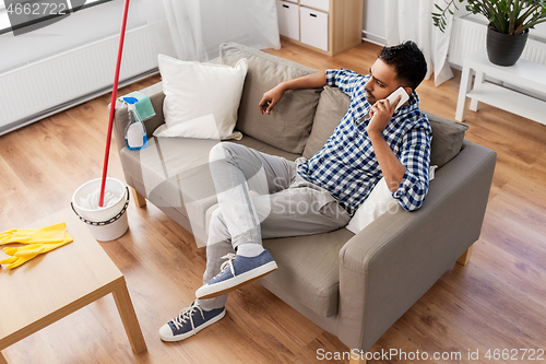 Image of man calling on smartphone after cleaning home