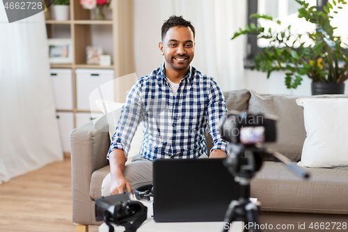 Image of male blogger with camera videoblogging at home