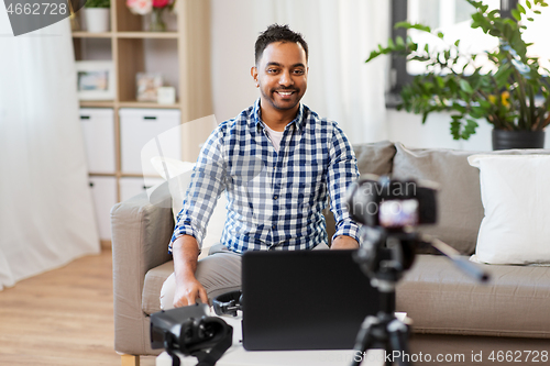 Image of male blogger with camera videoblogging at home