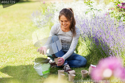 Image of woman filling pots with soil at summer garden