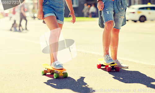 Image of teenage couple riding skateboards on city street