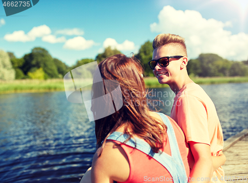 Image of happy teenage couple sitting on river berth