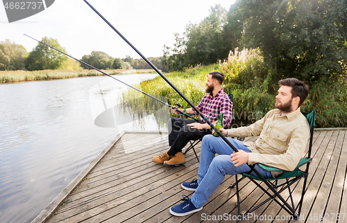 Image of male friends fishing and drinking beer on lake