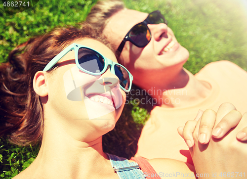 Image of happy teenage couple lying on grass at summer