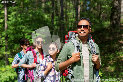 Image of group of friends with backpacks hiking in forest