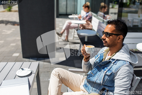 Image of indian man drinking coffee at city street cafe