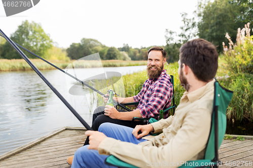 Image of male friends fishing and drinking beer on lake